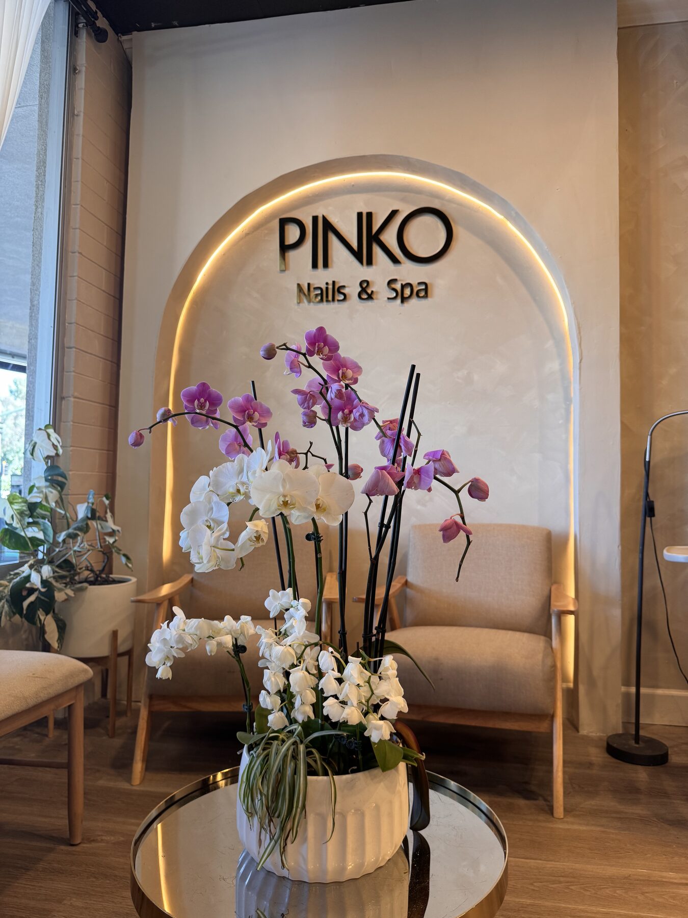 Fresh orchid arrangement framing the PINKO Nails & Spa archway.