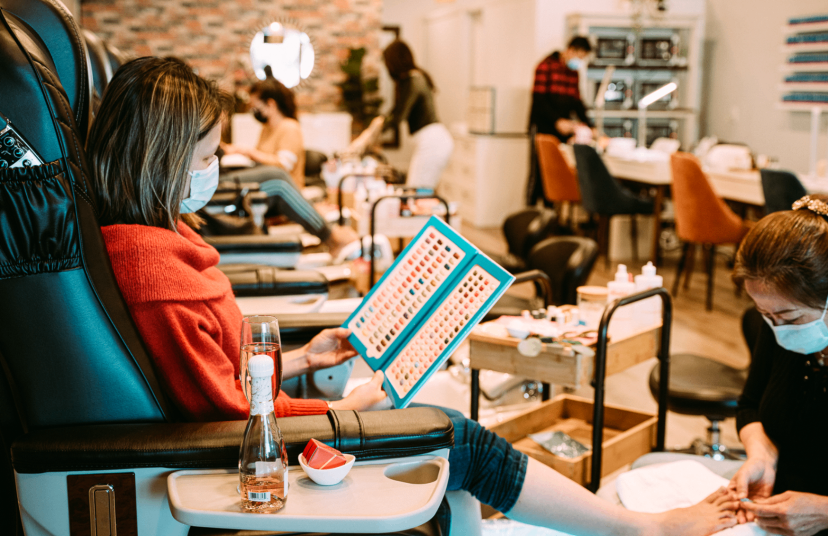 Guest relaxing during a pedicure at Pinko, browsing the color book